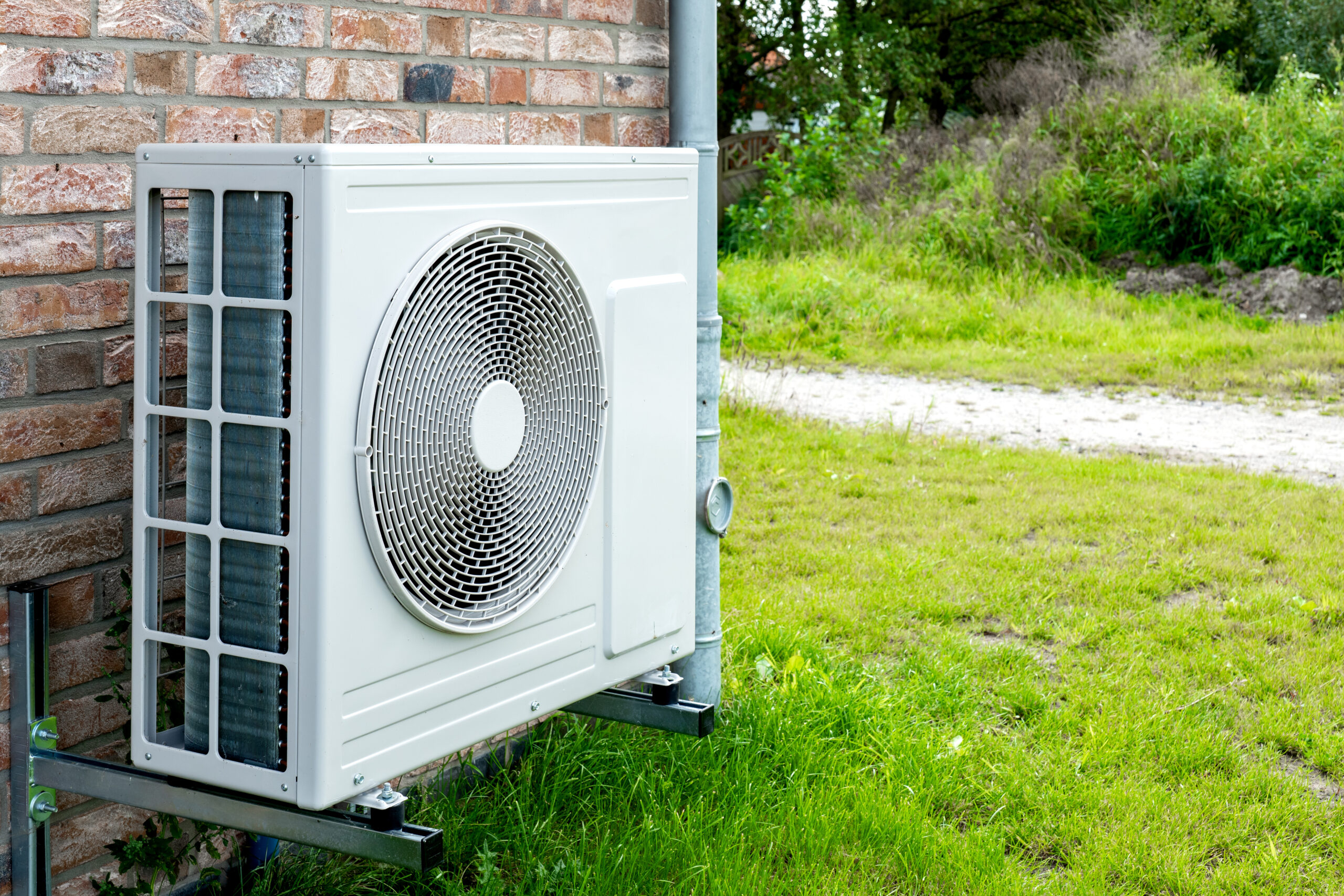 Heat pump unit installed outdoors near a brick house.